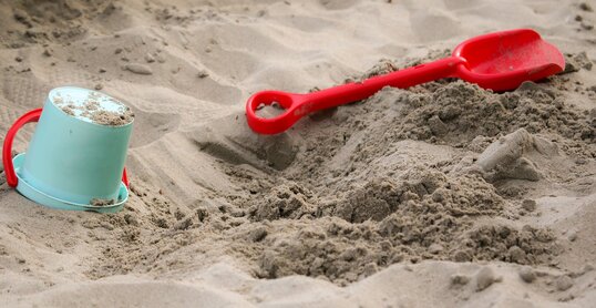 Sandkasten mit Schaufel und Eimer