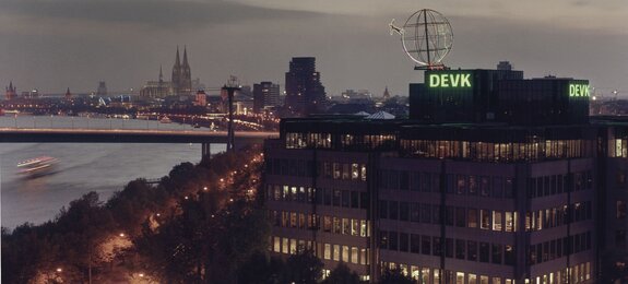 Foto der Firmenzentrale der DEVK mit Kölner Skyline im Hintergrund im Abendlicht