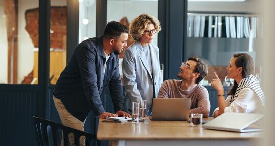 Gruppe von Geschäftsleuten in einer Besprechung vor einer SharePoint Site