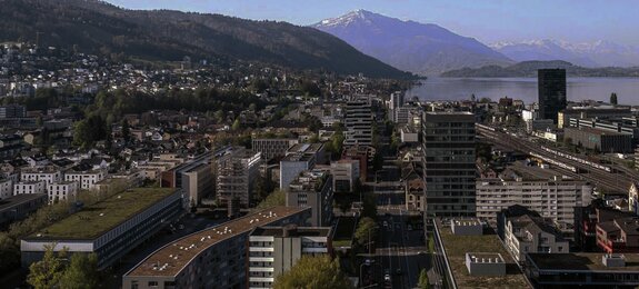 Ein Panorama der Stadt Zug mit See und Bergen im Hintergrund.